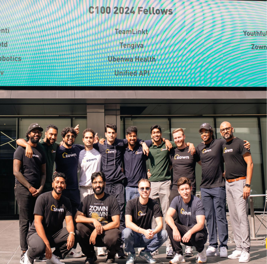 Zown team in front of the C100 2024 Fellows billboard featuring Zown as a selected company